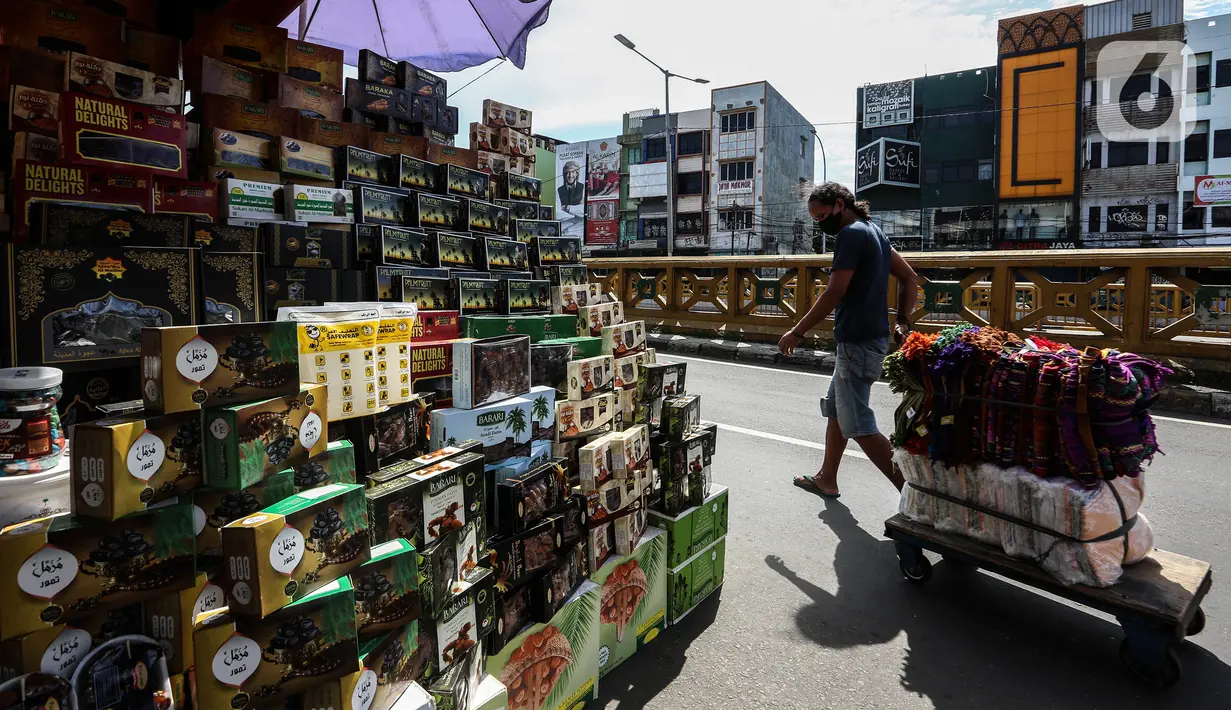 Seorang pria melewati kios pedagang kurma di kawasan Tanah abang, Jakarta, Minggu (3/4/2022). Omset penjualan kebutuhan bulan Ramadhan seperti perlengkapan ibadah dan buah kurma kembali meningkat dibandingkan dua tahun terakhir yang terdampak pandemi COVID-19. (Liputan6.com/Johan Tallo)