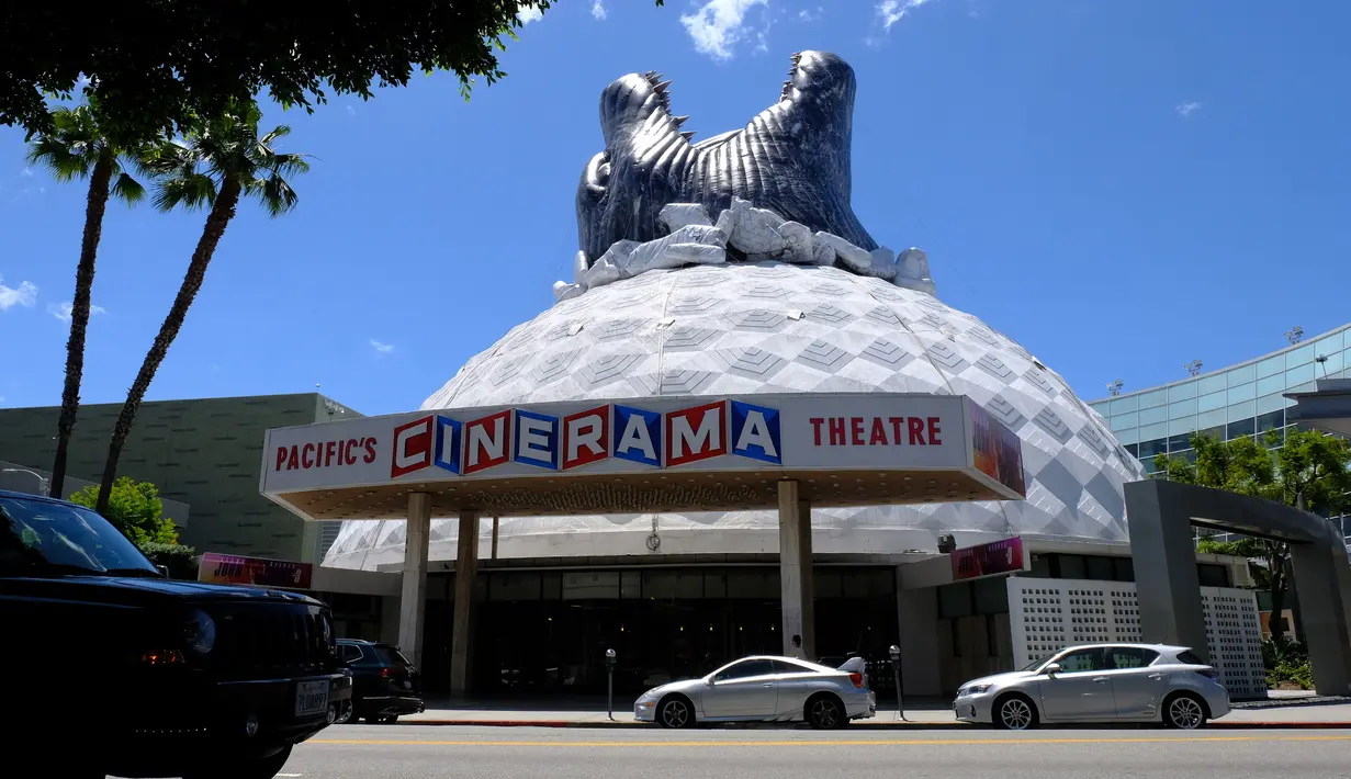 Kendaraan melintasi bioskop Cinerama Dome yang atapnya dihiasi godzilla raksasa di Hollywood, California, AS pada 20 Mei 2019. Hinggapnya godzilla raksasa untuk menyambut sekuel Godzilla: King of the Monsters yang akan dirilis pada 31 Mei 2019. (Photo by Chris Delmas / AFP)