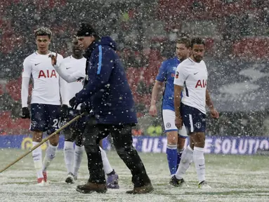 Seorang petugas membersikan salju dari alapangan saat babak kelima Piala FA antara Tottenham Hotspur melawan Rochdale di Wembley stadium, London, (28/2/2018). Tottenham menang 6-1. (AP/Matt Dunham)