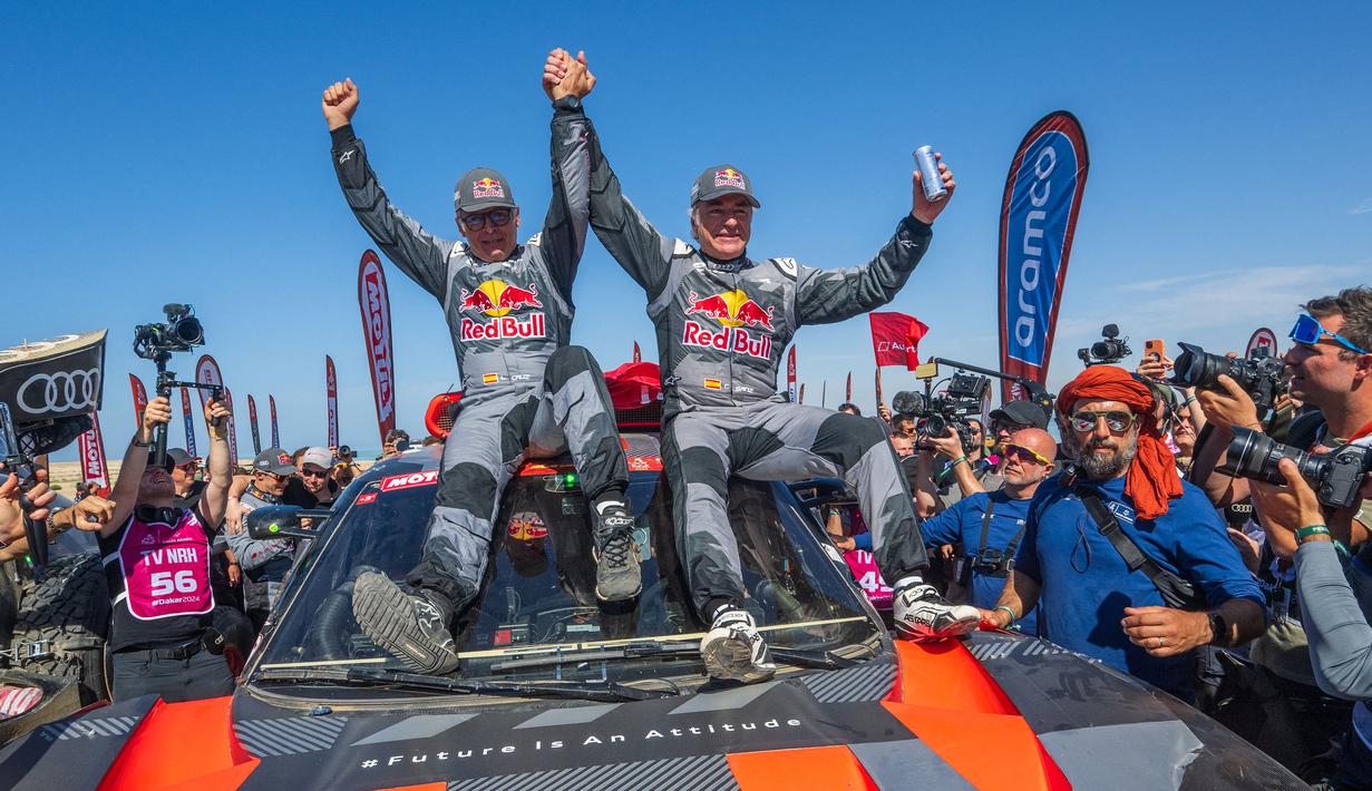 Pembalap Team Audi Sport, Carlos Sainz (kanan) dan co-driver, Lucas Cruzof merayakan kemenangan setelah menyelesaikan etape terakhir Reli Dakar 2024 di Yanbu, Arab Saudi, Jumat, 19 Januari 2024 waktu setempat. (AFP/Patrick Hertzog)