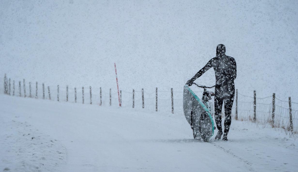 Seorang peselancar membawa papan selancar dengan sepeda menuju pantai di Lofoten Islands, Norwegia, (11/3/2018). Suhu udara minus 13°C dan suhu diatas air sekitar 4°C. (AFP/Oliver Morin)