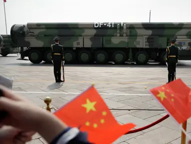 Warga mengibarkan bendera China saat kendaraan militer yang membawa Dongfeng-41 atau DF-41 melintas dalam parade militer di Beijing, 1 Oktober 2019. Rudal balistik antarbenua DF-41 menjadi sorotan pengamat dan ahli persenjataan dunia karena disebut dapat menjangkau wilayah AS. (AP/Mark Schiefelbein)
