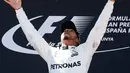 Pembalap Mercedes, Lewis Hamilton melemparkan trofi setelah memenangi balapan F1 GP Spanyol di Sirkuit Catalunya, Minggu (14/5). Meskipun memenangi GP Spanyol, Hamilton belum mampu merebut pimpinan klasemen dari Sebastian Vettel. (AP Photo/Manu Fernandez)