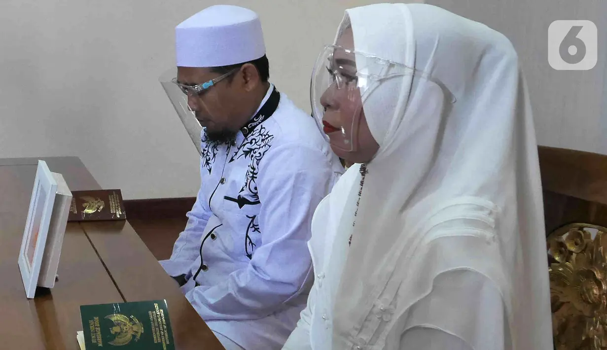 Pasangan Dewi dan Dinar saat melangsungkan pernikahan di KUA Kecamatan Meteng, Jakarta, Selasa (22/02/2022). Sejumlah pasangan sengaja melangsungkan pernikahan pada hari ini yang memiliki tanggal, bulan, dan tahun unik yakni 22-02-2022. (Liputan6.com/Herman Zakharia)