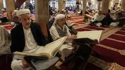 Sejumlah pria membaca Al-Quran selama bulan Ramadan di Masjid Agung Sanaa, Yaman, Minggu (26/4/2020). Kaligrafi dan dekorasi merupakan kekhasan Masjid Agung Sanaa. (Mohammed HUWAIS/AFP)