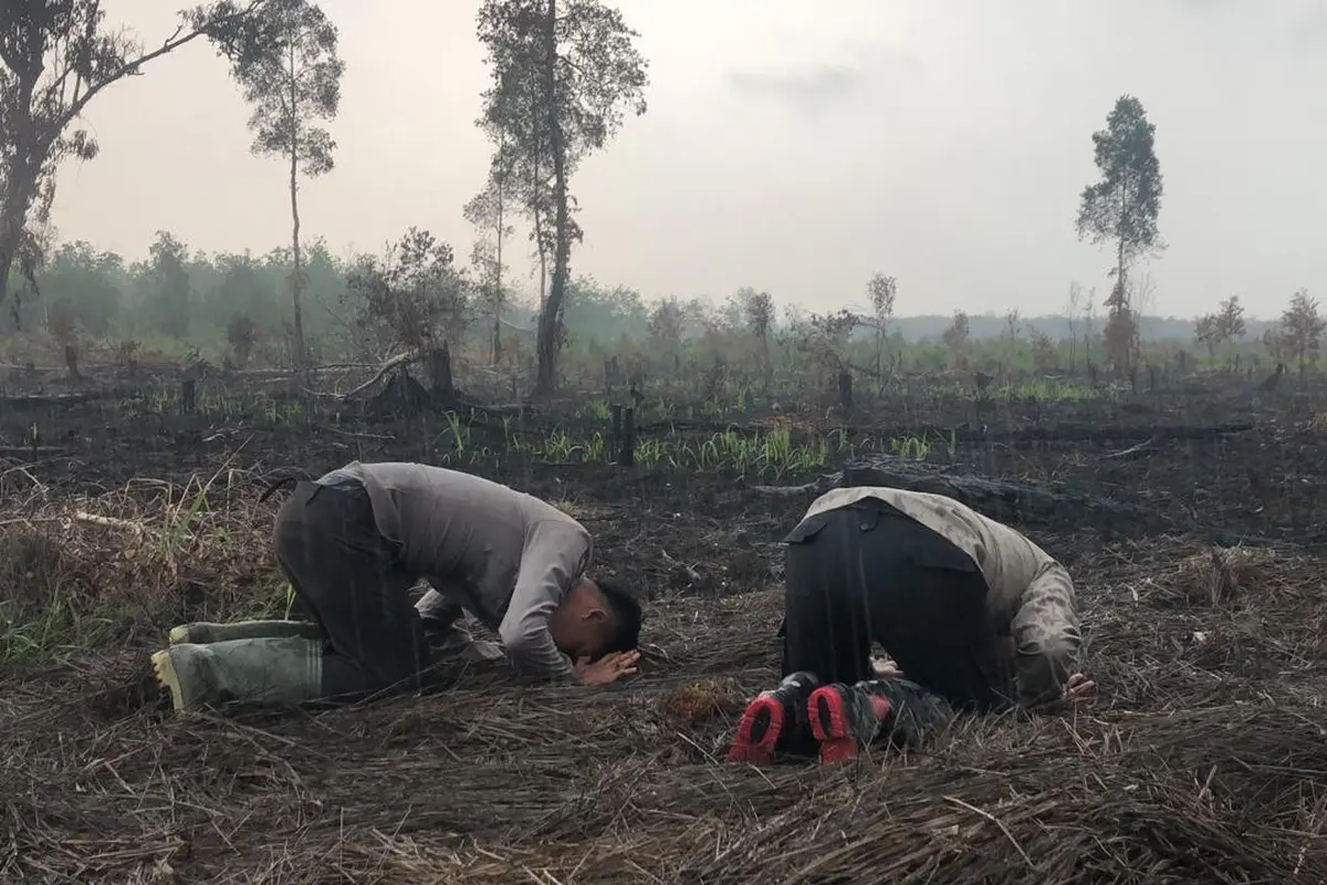 Anggota polisi Satgas Karhutla sujud syukur hujan turun.