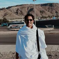 Arya Saloka tampil mengenakan ihram yang menjadi baju khusus untuk pria saat umrah. Ia pun melengkapi tampilannya dengan tas hitam dan kacamata hitamnya. [@arya.saloka]