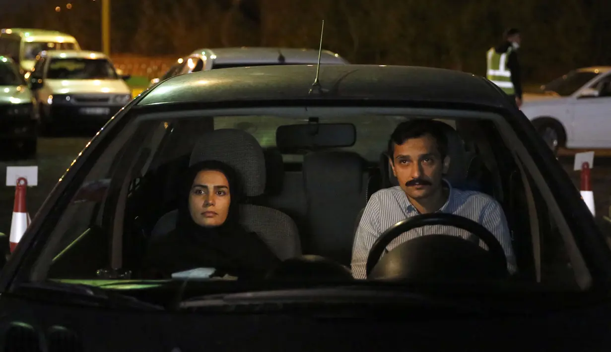 Warga duduk dalam mobil saat upacara keagamaan pada bulan suci Ramadan di tengah pandemi COVID-19, Teheran, Iran, Kamis (30/4/2020). Keluarga-keluarga di Iran menghadiri upacara keagamaan drive-in karena tidak memiliki kesempatan untuk salat di masjid setelah berbuka puasa. (STR/AFP)