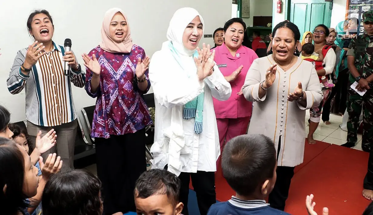 Ketum Bhayangkari, Tri Suswati Tito Karnavian bersama Polwan melakukan trauma healing dengan mengajak bernyanyi dan bermain bersama anak-anak  korban bencana banjir Sentani di Kabupaten Jayapura, Papua, Jumat (22/3).(Liputan6.com/Pool/Humas Mabes Polri)