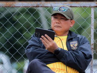 Manajer Timnas Indonesia U-22, Sumardji, tampak serius menyaksikan laga Timnas Vietnam U-22 vs Timnas Malaysia U-22 dari layar handphone. (Bola.com/Bagaskara Lazuardi)