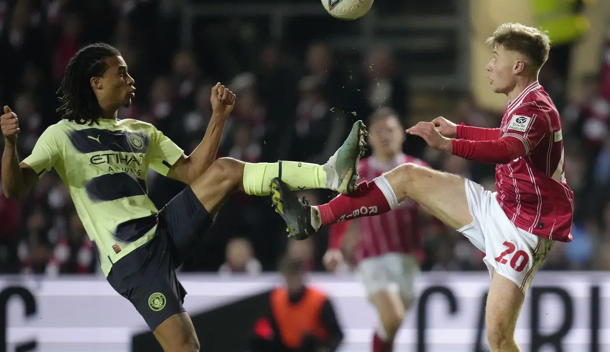 Bek Manchester City Nathan Ake berebut bola dengan penyerang Bristol City Sam Bell pada putaran ke-5 Piala FA 2022/2023 di Ashton Gate Stadium, Rabu dini hari (1/3/2023). Phil Foden menyumbang dua gol dalam laga ini, dan satu lagi dilesakkan Kevin De Bruyne. (AP Photo/Kirsty Wigglesworth)