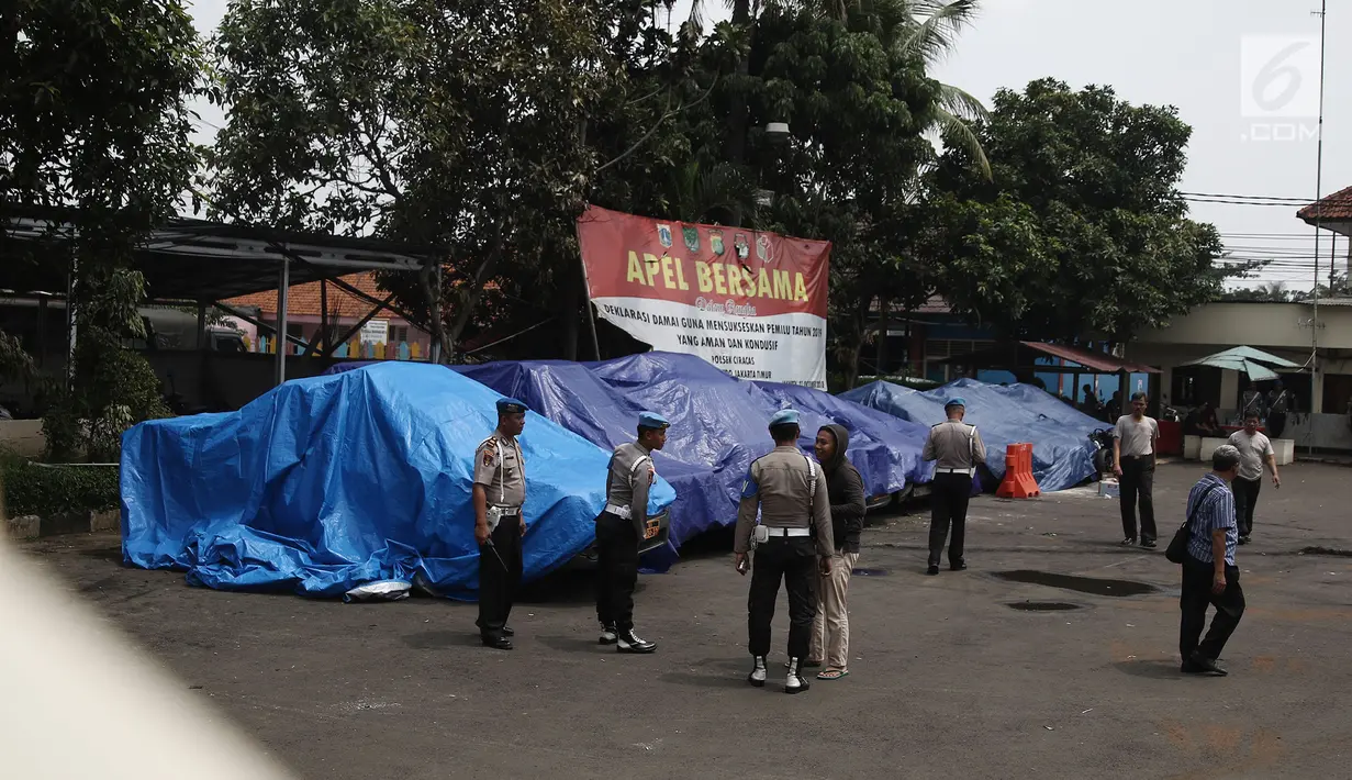 Terpal menutupi sejumlah mobil yang dirusak di Polsek Ciracas, Jakarta, Rabu (12/12). Aksi massa tersebut diduga akibat tidak puas dengan penanganan kasus di Polsek Ciracas. (Liputan6.com/Herman Zakharia)