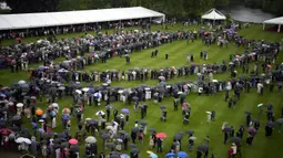 Para tamu berbaris berlindung di bawah payung dari hujan saat mereka menunggu anggota keluarga Kerajaan Inggris termasuk Pangeran Charles dan istrinya Camilla the Duchess of Cornwall tiba pada pesta kebun pertama musim ini di Istana Buckingham, London, Inggris, Mei 11 Februari 2022. Pesta kembali untuk pertama kalinya sejak 2019 setelah wabah virus corona COVID-19. (AP Photo/Matt Dunham, Pool)