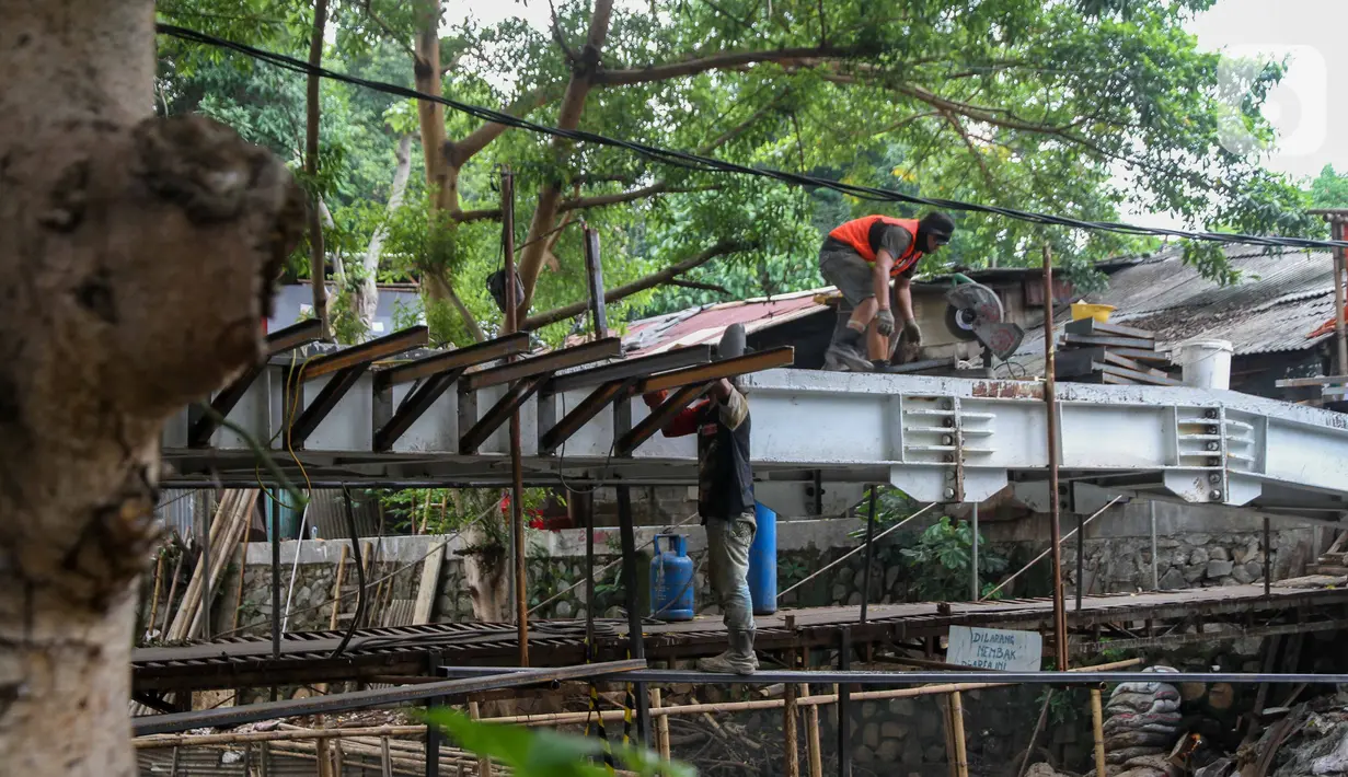 Pekerja menyelesaikan proyek pembangunan jembatan penghubung antarkampung di kawasan Pondok Pinang, Jakarta, Jumat (13/12/2019).  Jembatan yang menghubungkan permukiman di daerah Pondok Pinang dengan kawasan Bintaro tersebut ditargetkan rampung pada akhir Desember. (Liputan6.com/Faizal Fanani)