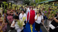 Seorang pemuka agama Katolik memberkati umat yang memegang daun palem di sepanjang jalan selama prosesi untuk menandai Minggu Palma sebagai bagian dari devosi jelang perayaan Paskah di Manila, Filipina pada 13 April 2025. (Ted ALJIBE/AFP)