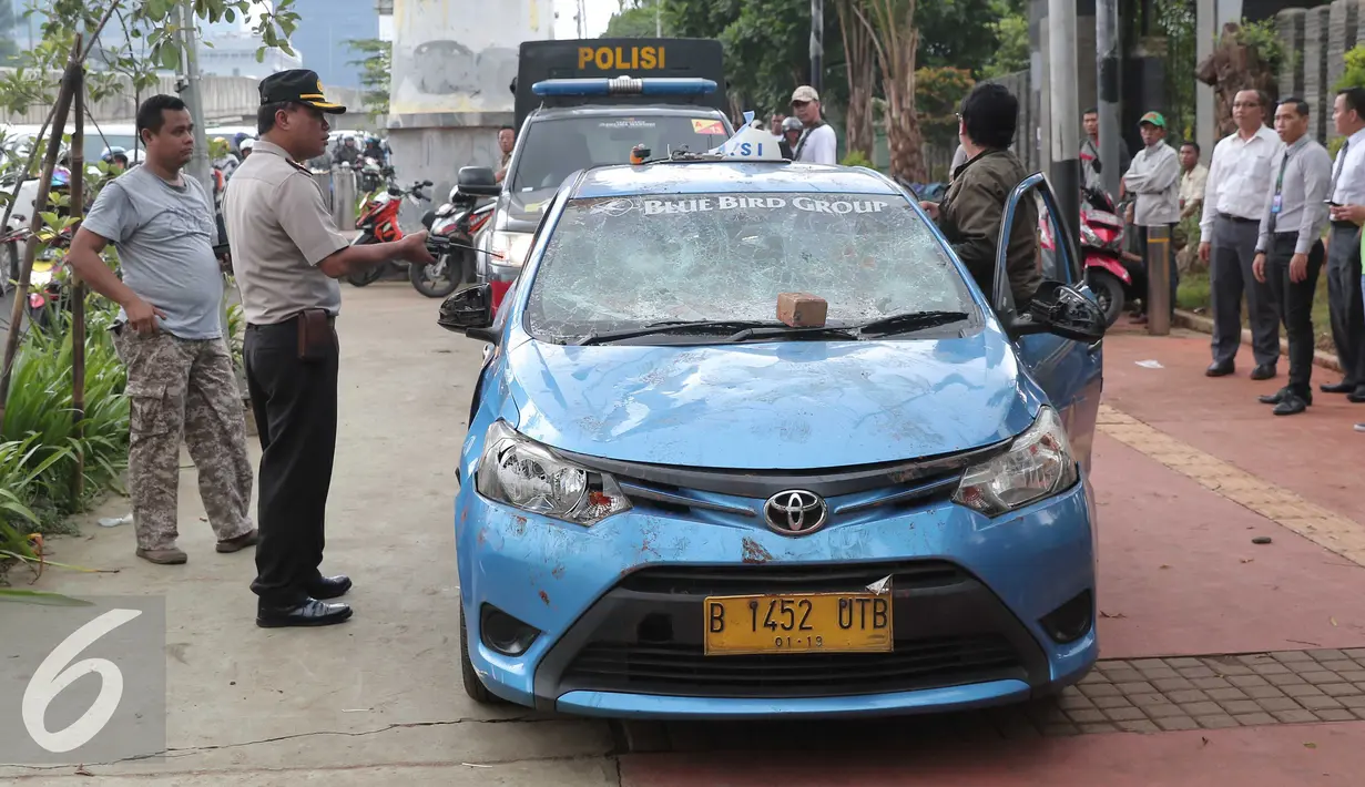 Petugas mengamankan mobil taksi yang hancur akibat dirusak oleh ojek online di Jakarta, Selasa (22/3). Akibat aksi saling serang antara taksi dan ojek online berimbas pada kerusuhan yang terjadi di beberapa titik di Jakarta. (Liputan6.com/Angga Yuniar)