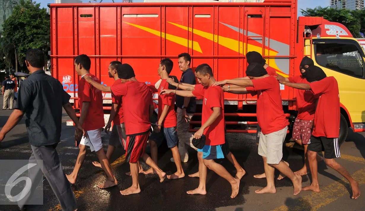 Tersangka berjalan dikawal petugas usai rilis hasil cipta kondisi akhir tahun di Polda Metro Jaya, Jakarta (30/12). Barang bukti dan tersangka dihadirkan dari seluruh Polres dan Polsek sejabodetabek. (Liputan6.com/Gempur M Surya)