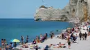 Wisatawan berjemur di pantai di Etretat, Prancis barat laut (17/7). Tebing-tebing dan pantai di Étretat menarik para seniman seperti Eugène Boudin, Gustave Courbet dan Claude Monet. (AFP Photo/Charly Triballeau)