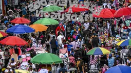 Kepadatan jalan komersial di San Victorino saat orang-orang berbelanja hadiah Natal di Bogota, Kolombia, Senin (21/12/2020). Kota-kota utama di Kolombia pada Senin mengumumkan pembatasan yang mempengaruhi sekitar 15 juta orang karena peningkatan penularan covid-19 menjelang Natal. (Juan BARRETO/AFP)
