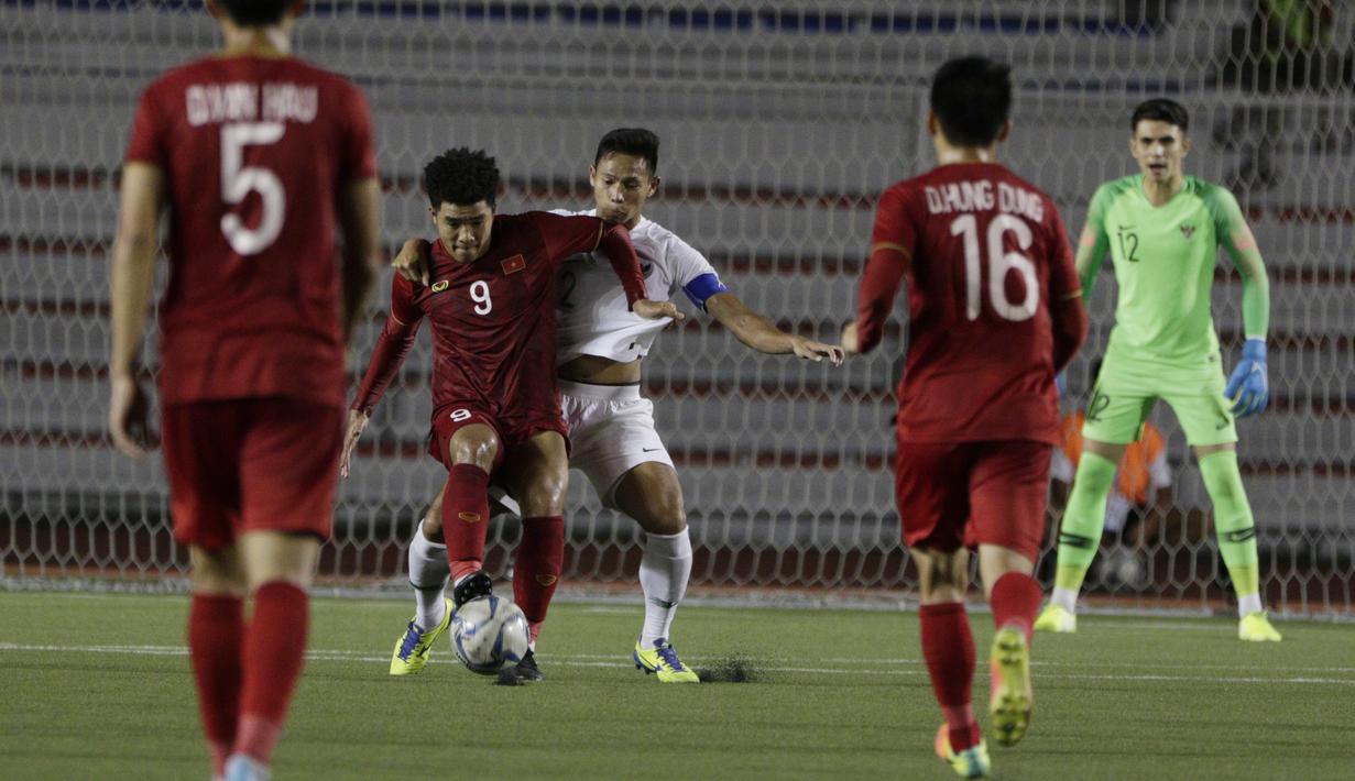 Bek Timnas Indonesia U-22, Andy Setyo, berebut bola dengan striker Vietnam U-22, Ha Duc Chinh, pada laga SEA Games 2019 di Stadion Rizal Memorial, Manila, Minggu (1/12). Indonesia kalah 1-2 dari Vietnam. (Bola.com/M Iqbal Ichsan)