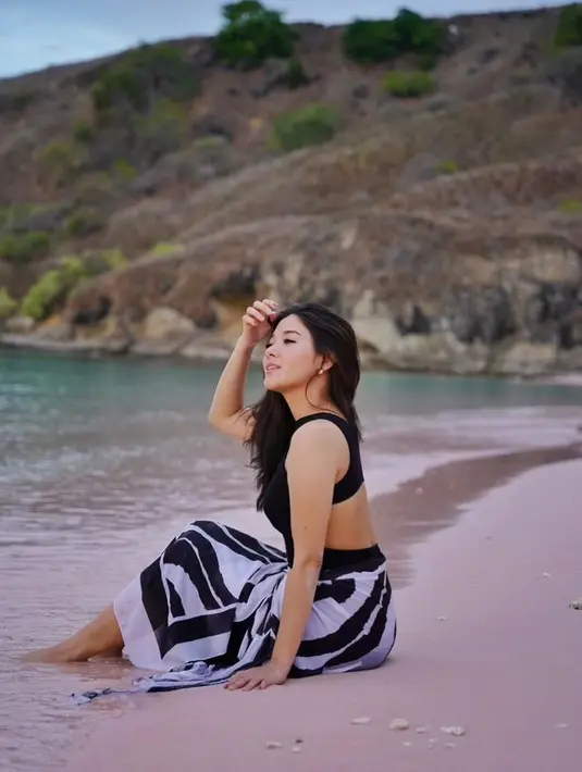 Berada di Pink Beach, Naysilla Mirdad mengenakan swimsuit hitam dipadukan kain warna putih salur hitam. [@naymirdad]