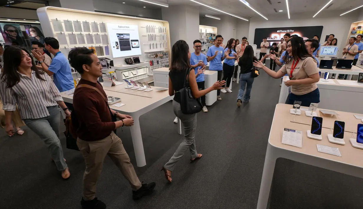 Para karyawan menyambut pelanggan yang memasuki toko mereka yang menjual Apple iPhone 16 di Jakarta pada 11 April 2025. (BAY ISMOYO/AFP)