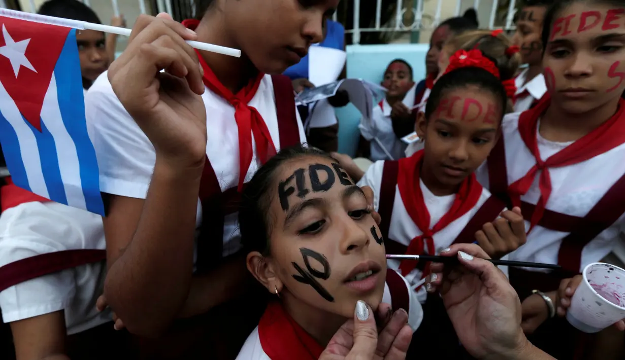 Sejumlah siswa melukis wajah mereka dengan tulisan Fidel saat menunggu mobil yang membawa abu mantan pemimpin Revolusi Kuba, Fidel Castro, lewat di Bayamo, Kuba (3/11). (Reuters/Enrique De La Osa)
