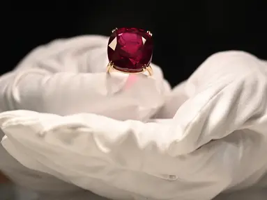 Perwakilan dari Sotheby's mengangkat Estrela de Fura Ruby, batu rubi terbesar di dunia, di Hong Kong pada 17 April 2023. (Photo by Peter PARKS / AFP)