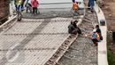 Pekerja menyelesaikan pembangunan jalan Inspeksi di kawasan kali Ciliwung Kalibata, Jakarta, Rabu (30/11). Keberadaan jalan ini diharapkan menambah ruang terbuka hijau, jalur pejalan kaki, dan jalur sepeda. (Liputan6.com/Gempur M Surya)