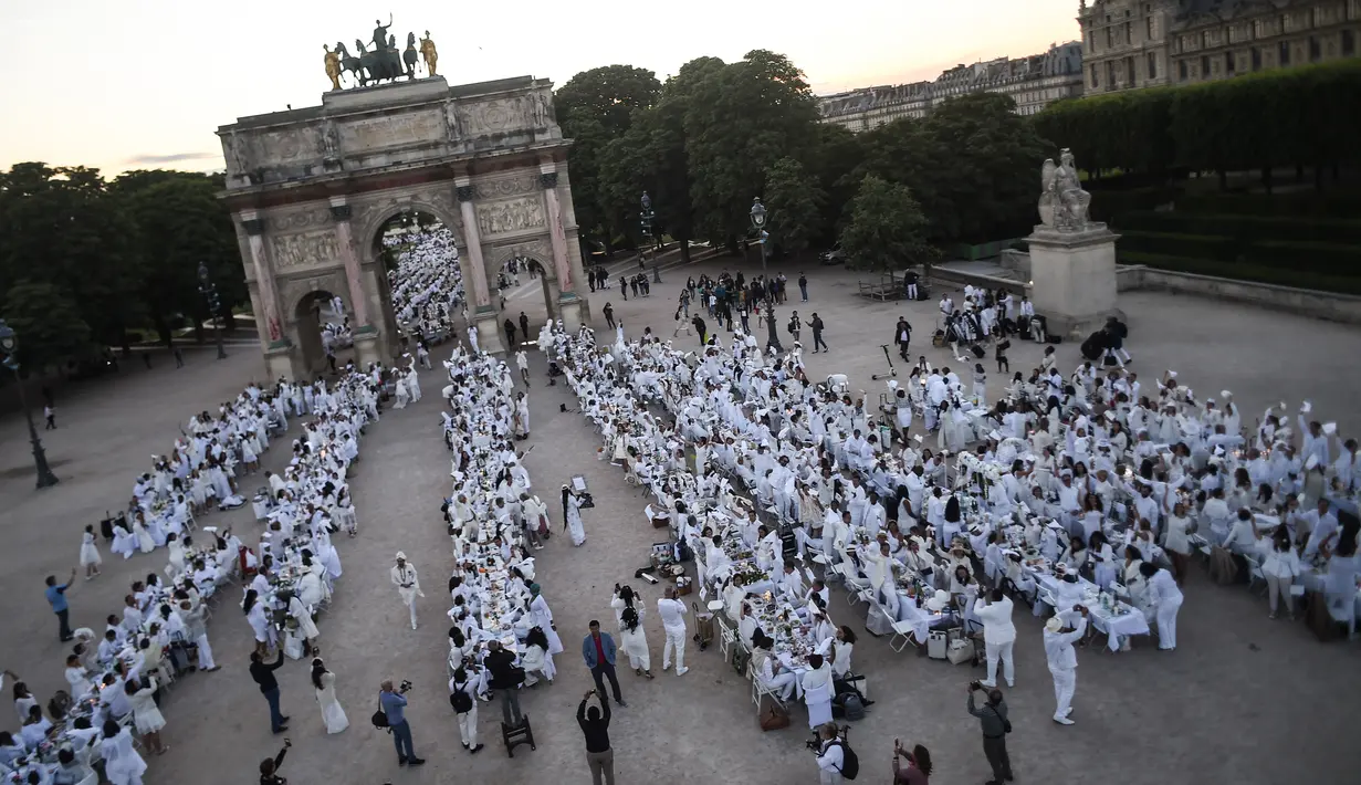 Para peserta dalam balutan serba putih  berkumpul untuk Dinner en Blanc atau "makan malam putih" di Tuileries Gardens, Paris, Kamis (6/6/2019). Gelaran yang berlangsung sejak 1988 ini dilengkapi dengan meja makan yang dihiasi taplak, kursi dan peralatan makan bernuansa putih. (Lucas BARIOULET/AFP)