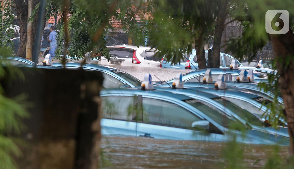 Sejumlah taksi terendam banjir di Pool Taksi Bluebird kawasan Kramat Jati, Jakarta, Selasa (25/2/2020). Meluapnya Kali Cipinang membuat Pool Taksi Blue Bird yang berada tepat di samping kali ikut terdampak banjir. (Liputan6.com/Herman Zakharia)