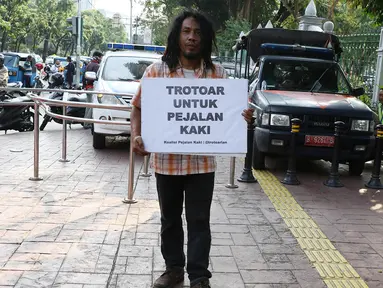 Aktivis Koalisi Pejalan Kaki (KPK) melakukan aksi sambil membawa poster himbauan di sepanjang trotoar kawasan Monas, Jakarta, Jumat (28/7). Aksi tersebut dilakukan untuk mengembalikan trotoar sesuai fungsinya. (Liputan6.com/Immanuel Antonius)