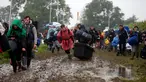 Penonton Festival Glastonbury tampak melewati jalanan yang banjir dan berlumpur saat tiba di Worthy Farm, Somerset, Inggris, (22/6). Festival Glastonbury merupakan festival musik paling populer di dunia. (REUTERS / Stoyan  Nenov)