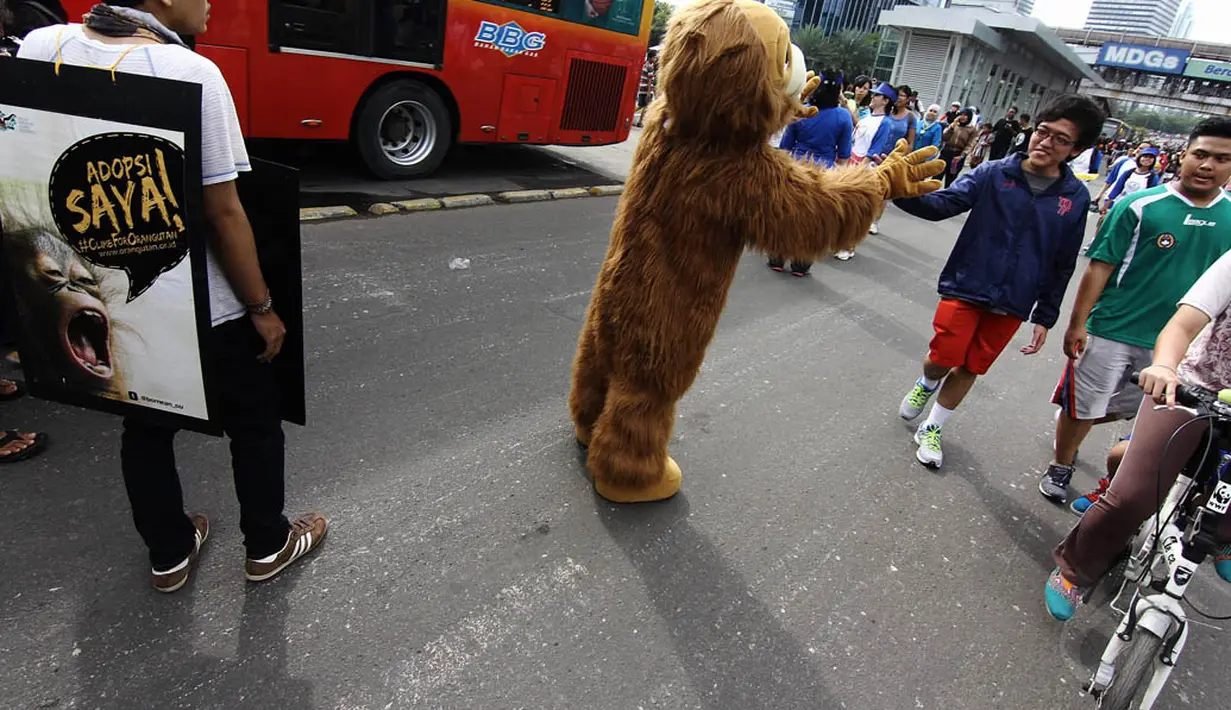 Seorang aktivis yang mengenakan kostum orangutan tampak menyapa warga di Jalan Sudirman, Jakarta, Minggu (30/11/2014).(Liputan6.com/Faizal Fanani)