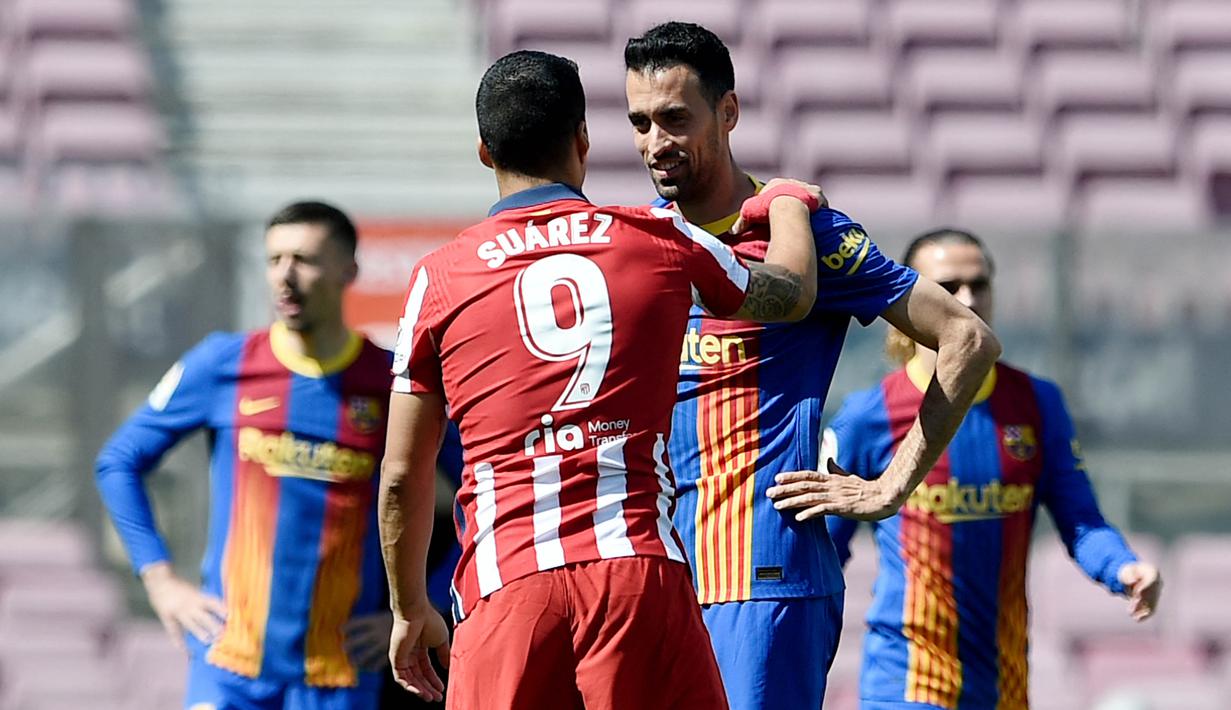 Striker Atletico Madrid, Luis Suarez, berbincang dengan gelandang Barcelona, Sergio Busquets, pada laga Liga Spanyol di Stadion Camp Nou, Sabtu (8/5/2021). Kedua tim bermain imbang 0-0. (AFP/Josep Lago)