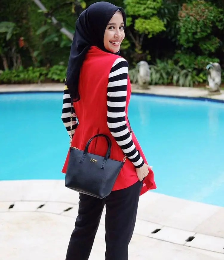 Bella kerap tampil casual dengan gaya hijabnya, memakai atasan garis-garis bersama vest merah, perpaduan warna yang terlihat matching. (sumber foto: @laudyacynthiabella/instagram)