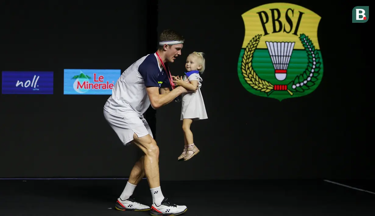 Pebulu tangkis tunggal putra Denmark, Viktor Axelsen, menggendong anaknya usai berhasil menjadi pemenang di nomor tunggal putra Indonesia Open 2022 usai mengalahkan pebulu tangkis tunggal putra China, Zhao Jun Peng pada babak di Istora Senayan, Jakarta, Minggu (19/06/2022). (Bola.com/Bagaskara Lazuardi)