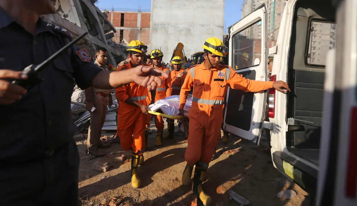 Petugas mengevakuasi jasad korban di lokasi gedung enam lantai yang ambruk di desa Shahberi, pinggiran kota New Delhi, India, Rabu (18/7). Bangunan ambruk kerap terjadi di India, apalagi di musim penghujan. (AP Photo/Altaf Qadri)