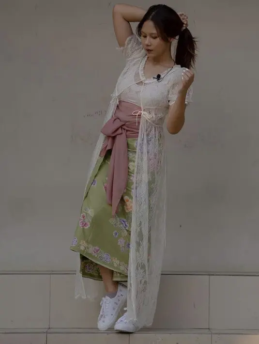 Nadin Amizah tampil casual dengan kain lilit hijau yang  dengan long outer model lace. Dipadukan dengan sneakers white. Dengan detail sabuk kain yang diikat pita @cakecaine