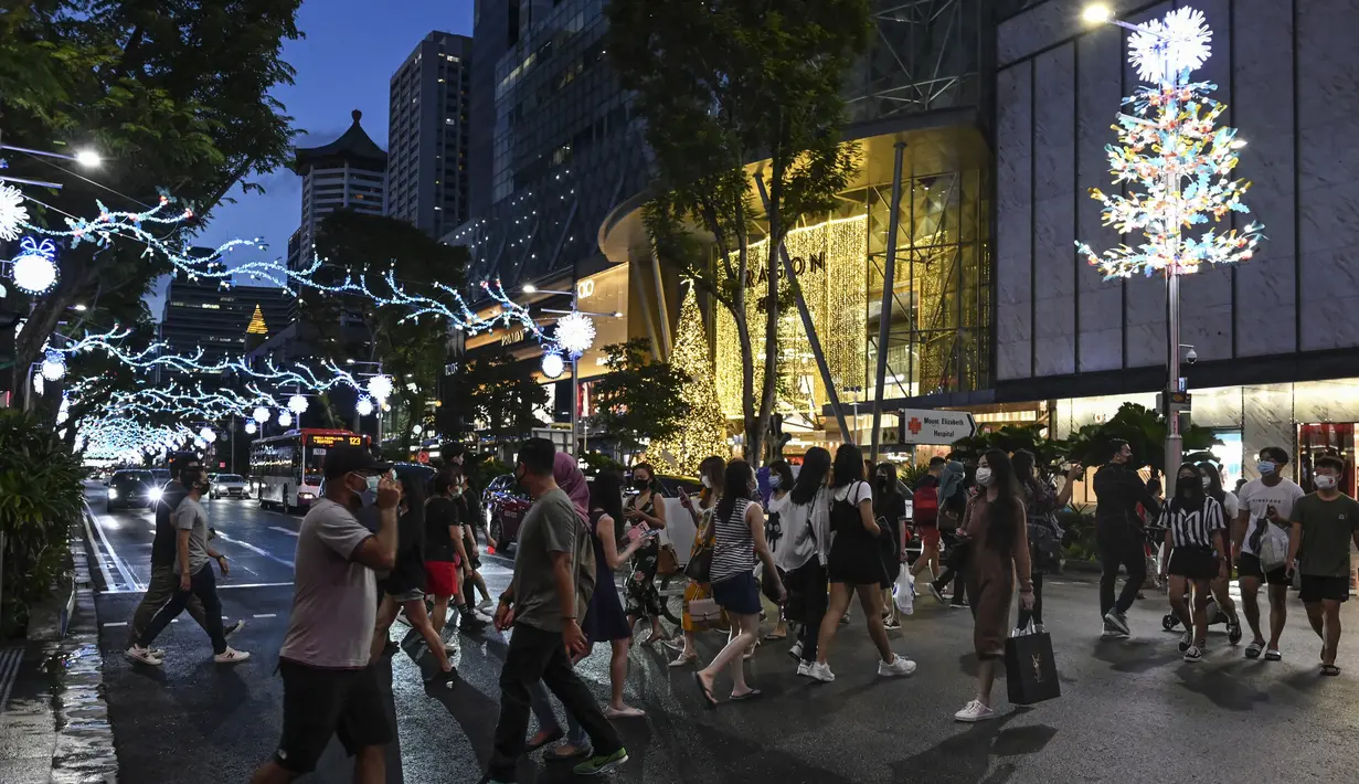 Pejalan kaki menyeberang jalan yang didekorasi dengan lampu Natal di distrik perbelanjaan Orchard road di Singapura, Selasa (8/12/2020). Mengusung tema Love This Christmas, acara tahun ini lebih sunyi karena aktivitas jalanan dibatasi di tengah pandemi Covid-19. (ROSLAN RAHMAN / AFP)