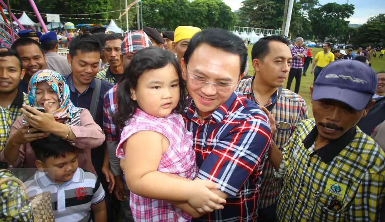 Cagub DKI Jakarta, Basuki T Purnama mengendong seorang anak saat menghadiri acara "Bersyukur Jakarta", Jumat (20/1). Dalam acara yang berbentuk bakti sosial dan pasar murah tersebut, terdapat hiburan dan permainan anak. (Liputan6.com/Immanuel Antonius)