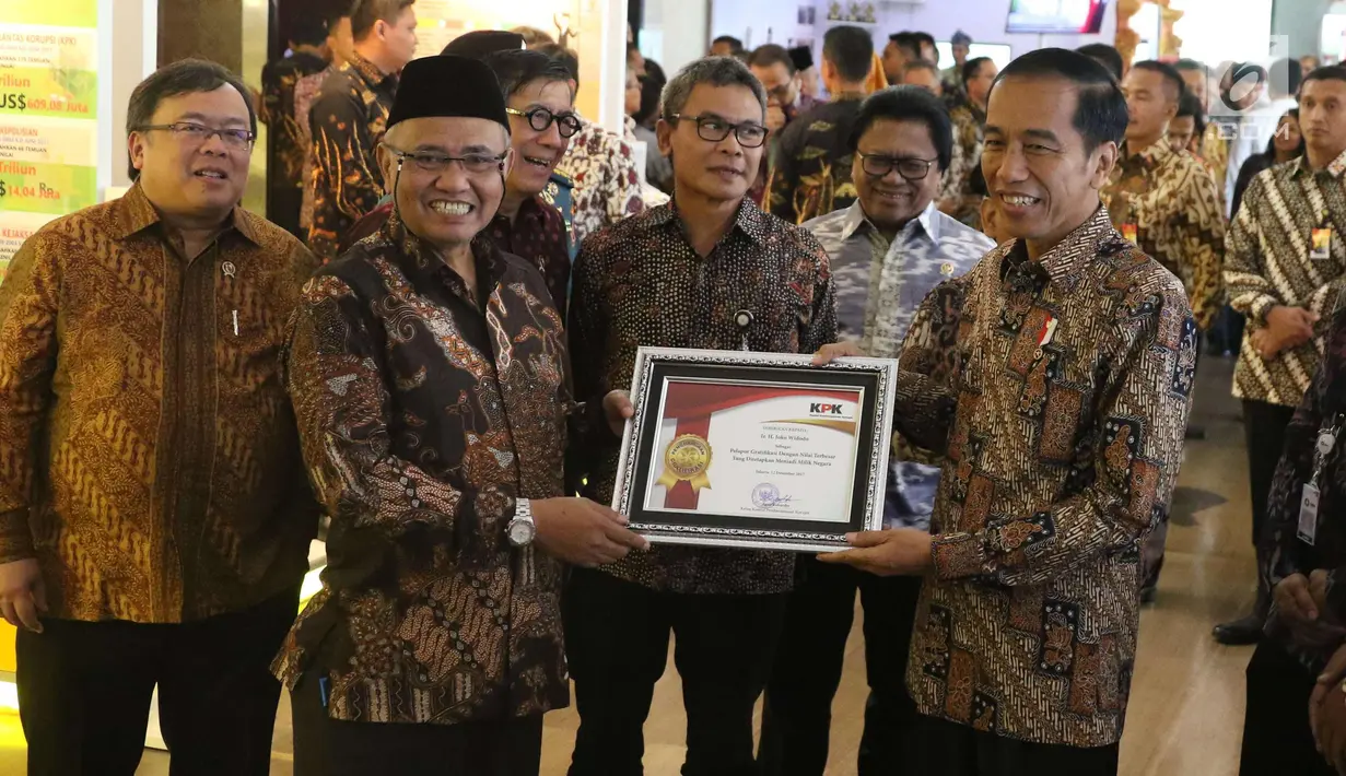 Presiden Jokowi menerima penghargaan sebagai pelapor gratifikasi dengan nilai terbesar yang ditetapkan menjadi milik negara dari Ketua KPK, Agus Rahardjo pada peringatan hari Antikorupsi Dunia, Jakarta, Senin (11/12). (Liputan6.com/Angga Yuniar)