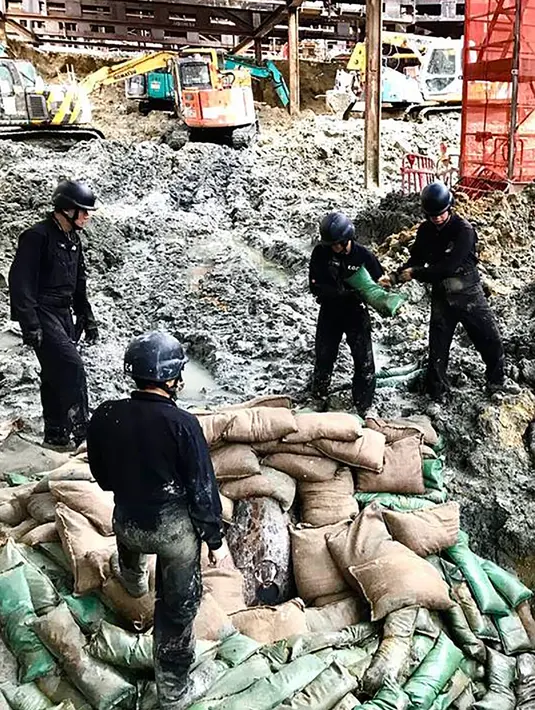 Polisi dari unit pejinak bom menempatkan karung pasir untuk mengamankan bom buatan AS yang dijatuhkan pada Perang Dunia II di persimpangan Convention Avenue dan Hung Hing Road di distrik Wan Chai di Hong Kong (11/5). (Handout / Polisi Hong Kong / AFP)