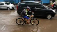 Seorang warga menggunakan sepedanya mencoba menerobos genangan air di Jalan Cikini Raya, Jakarta, Sabtu (7/11). Meski baru pertama kali diguyur hujan selama musim kemarau, jalan tersebut langsung terendam air. (Liputan6.com/ Immanuel Antonius)
