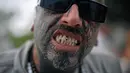 Seorang pria menunjukka anting yang ada di dekat giginya serta wajah yang dipenuhi tato saat acara Tattoo Week tahunan di Rio de Janeiro, Brasil (12/1). (AFP Photo/Mauro Pimentel)