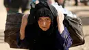 Seorang wanita membawa barang-barangnya menuju kamp pengungsian Khazer, Irak(28/11). Mereka pergi meninggalkan daerah yang sebelumnya dikuasai kelompok militan ISIS untuk mengungsi ke tempat yang lebih aman. (Reuters/Mohammed Salem)