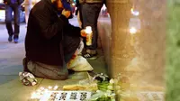 Seorang pria meletakkan lilin di depan Kedutaan Prancis di San Francisco, California sebagai penghormatan kepada korban serangan Paris. (Reuters)