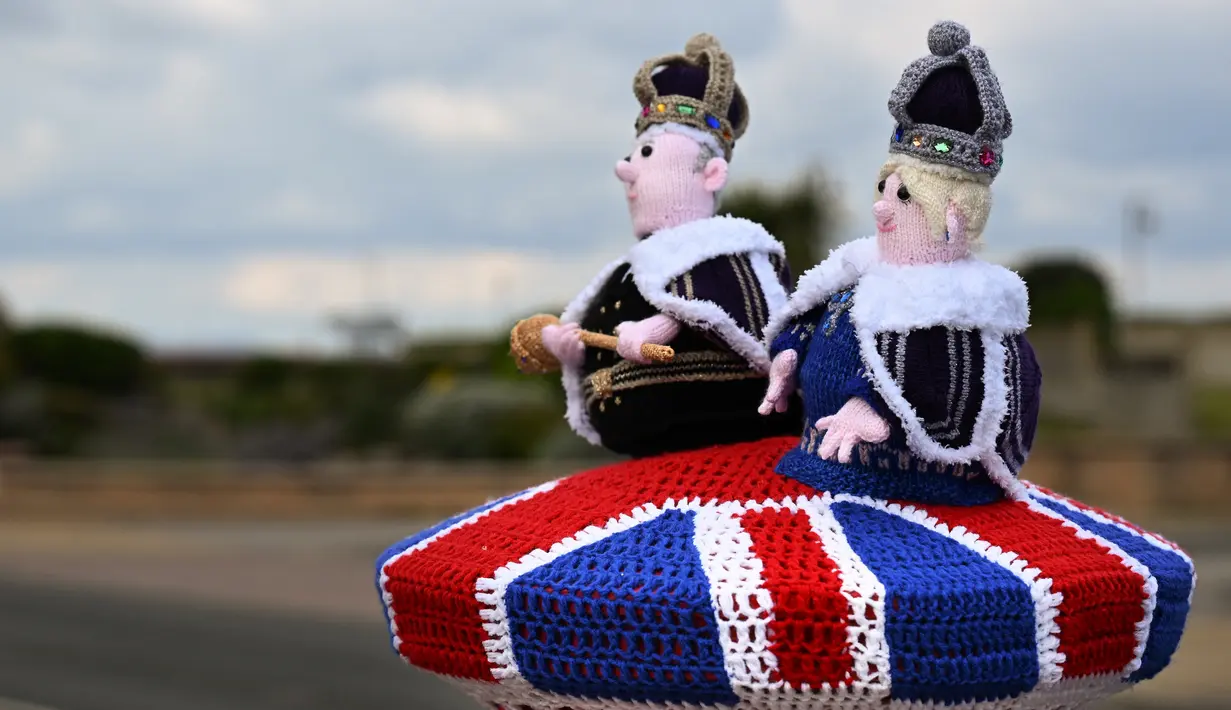 Sebuah foto pada 2 Mei 2023 menunjukkan rajutan Raja Charles III dan Permaisuri Camilla yang dipajang di kotak pos di sebelahnya, di Rhyl, Wales utara, menjelang upacara penobatan. (Photo by Paul ELLIS / AFP)
