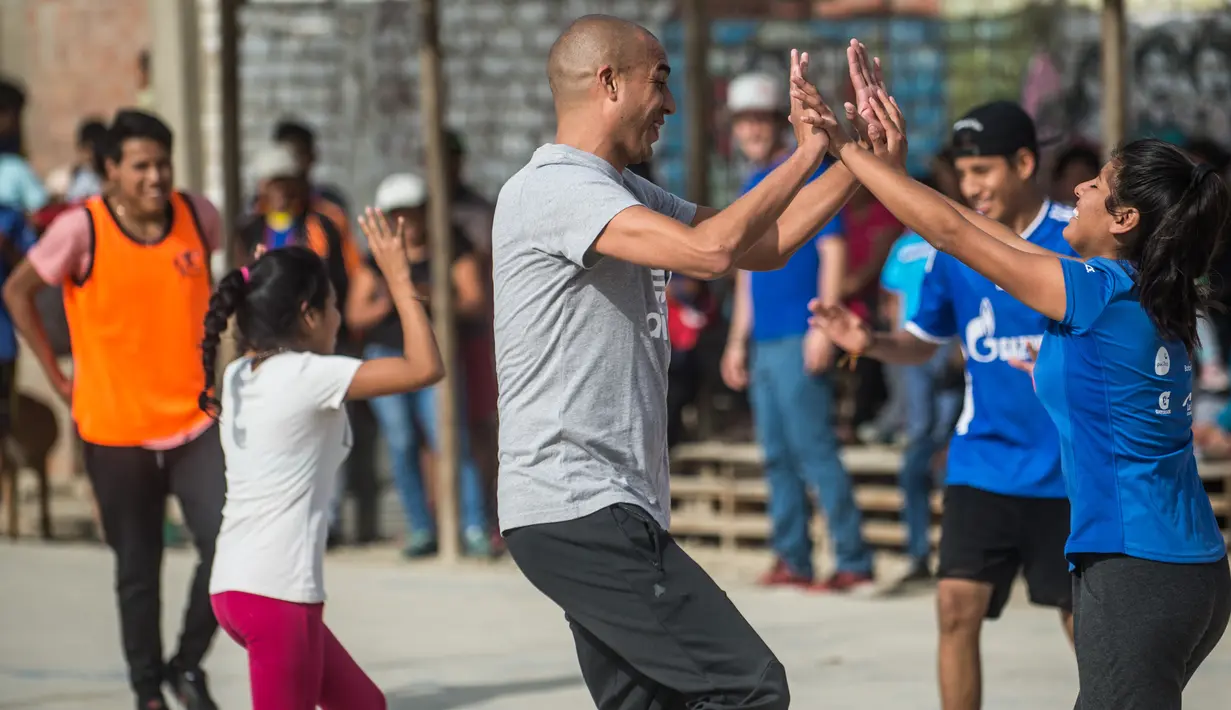 Mantan pemain bola Juventus, David Trezeguet merayakan golnysa saat bermain bola bersama anak-anak di komunitas San Pablo Mirador, Peru (13/7). (AFP Photo/Ernesto Benavides)