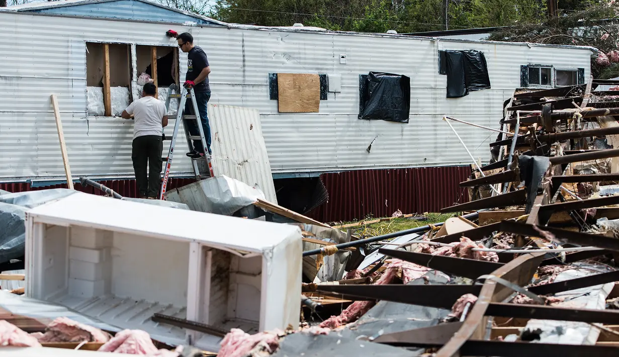 Dua orang pria memperbaiki tempat tinggal mereka yang rusak usai diterjang badai di Elon, Virginia (16/4). Akibat badai ini sejumlah rumah rusak berat. (Jay Westcott/The News & Advance via AP)